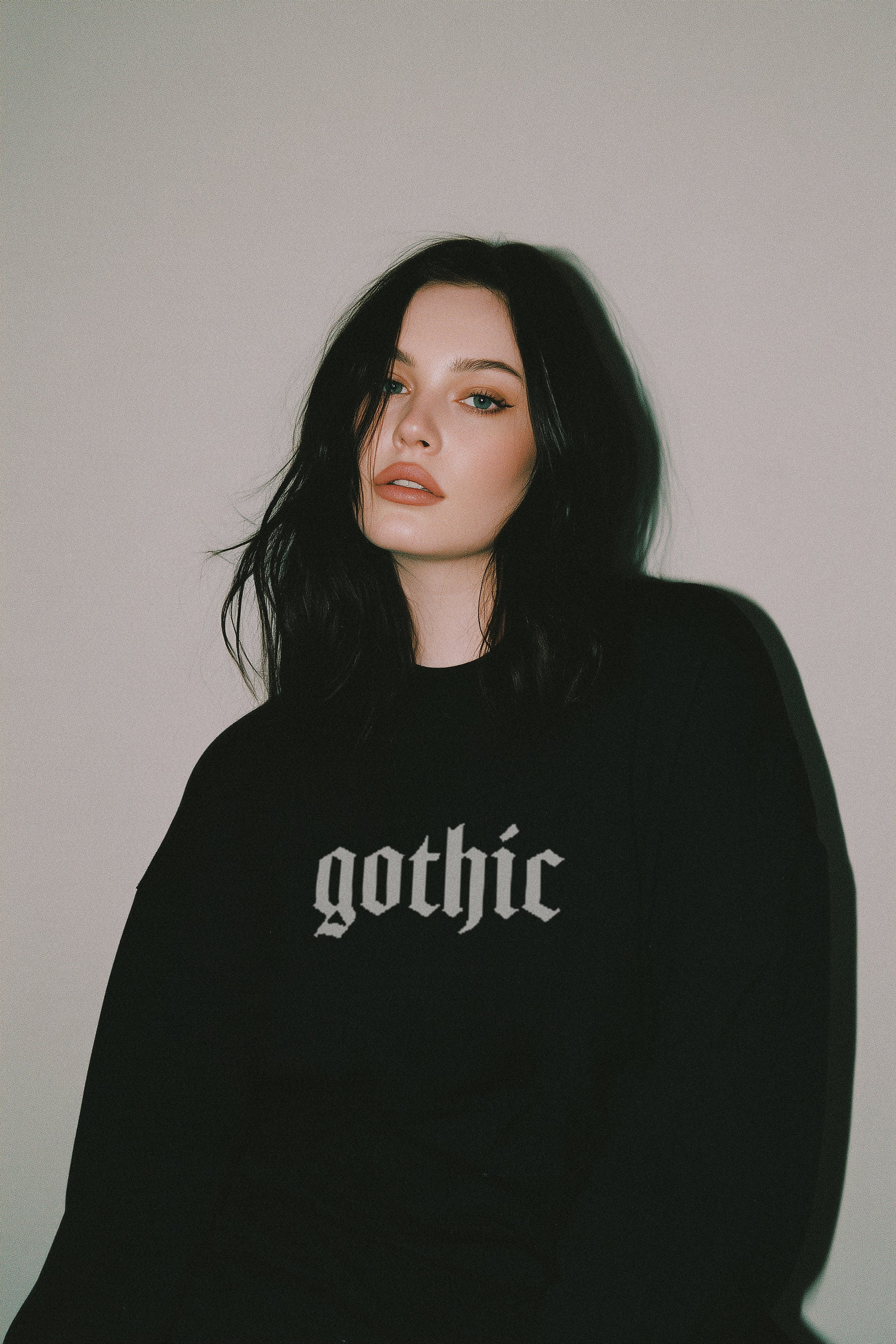 Person wearing a black sweatshirt with 'gothic' text against a plain background