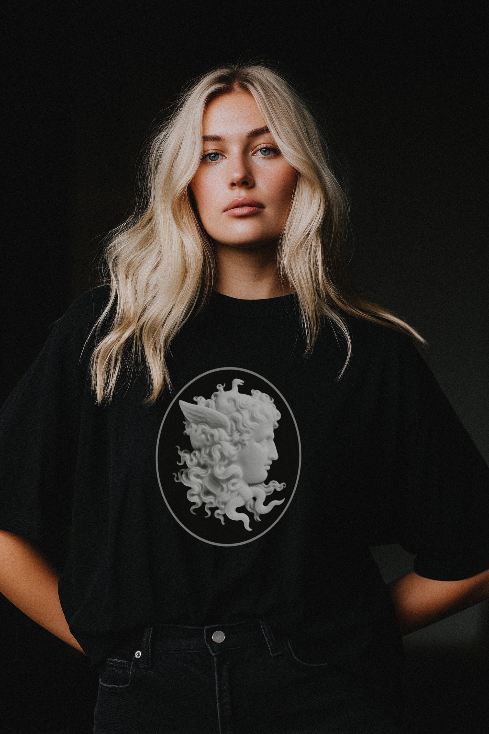 Person wearing a black t-shirt with a Medusa graphic on a dark background