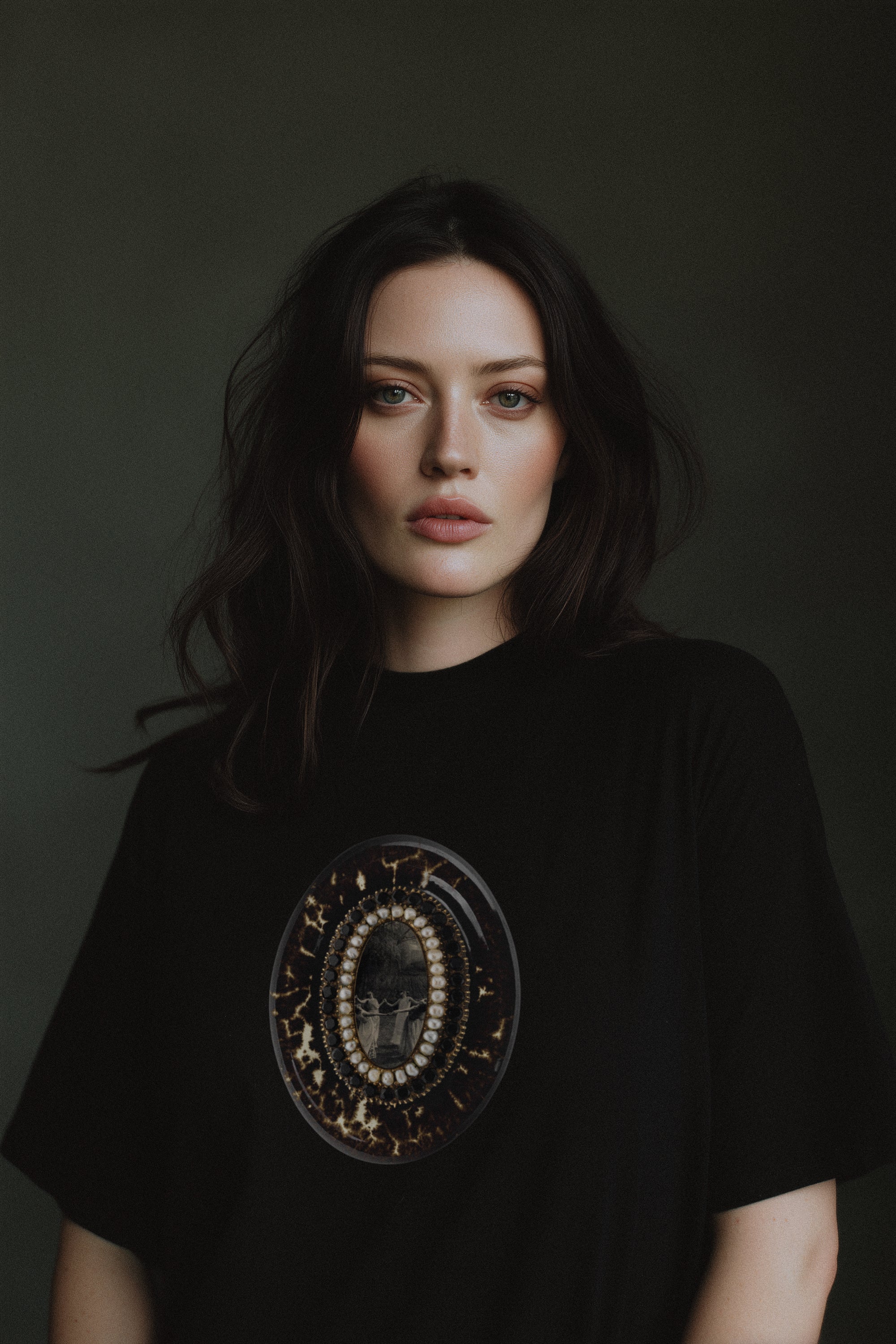 Person wearing a black t-shirt with a circular design on a dark background