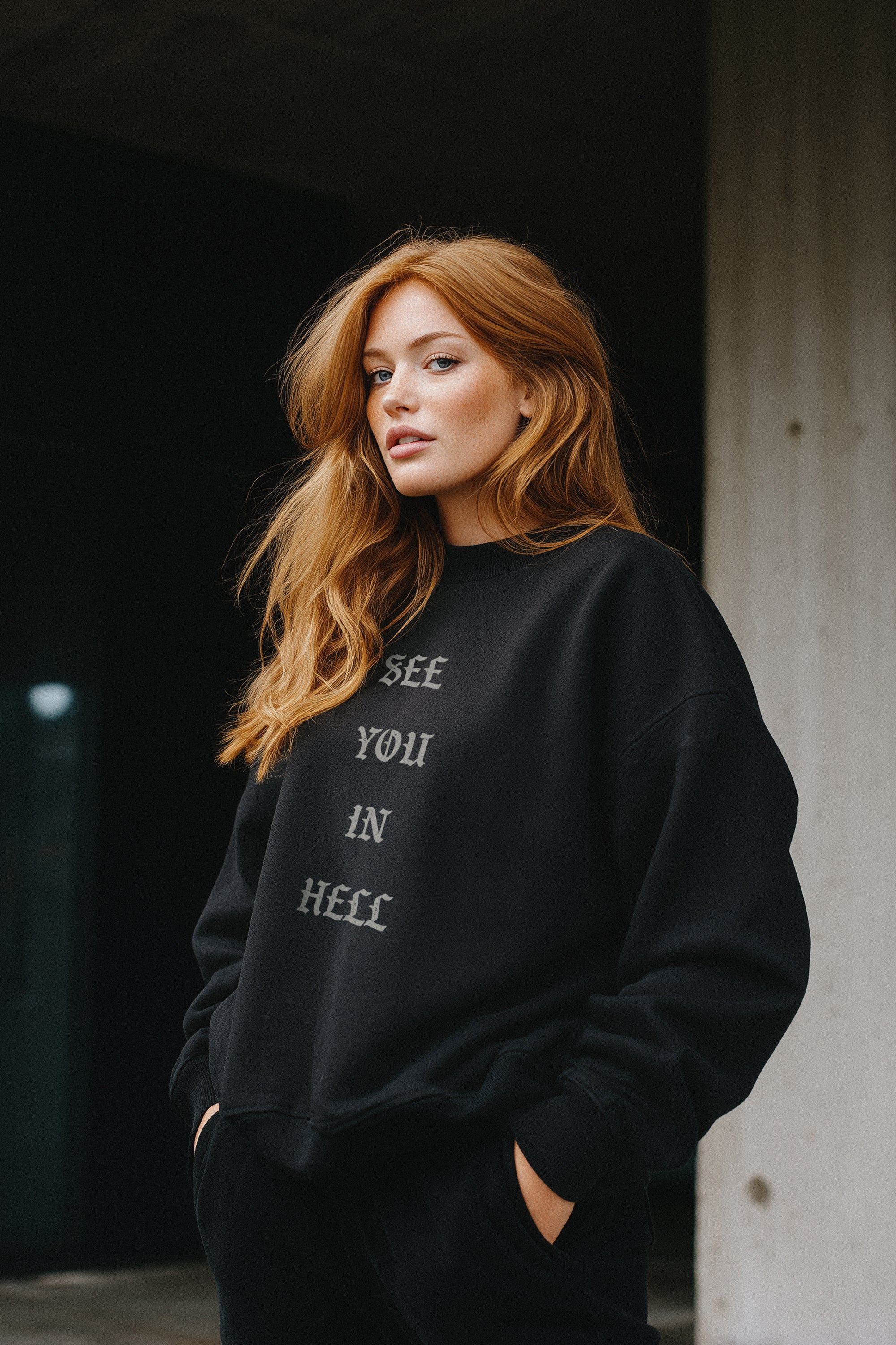 Woman wearing a black sweatshirt with text, standing against a dark background.