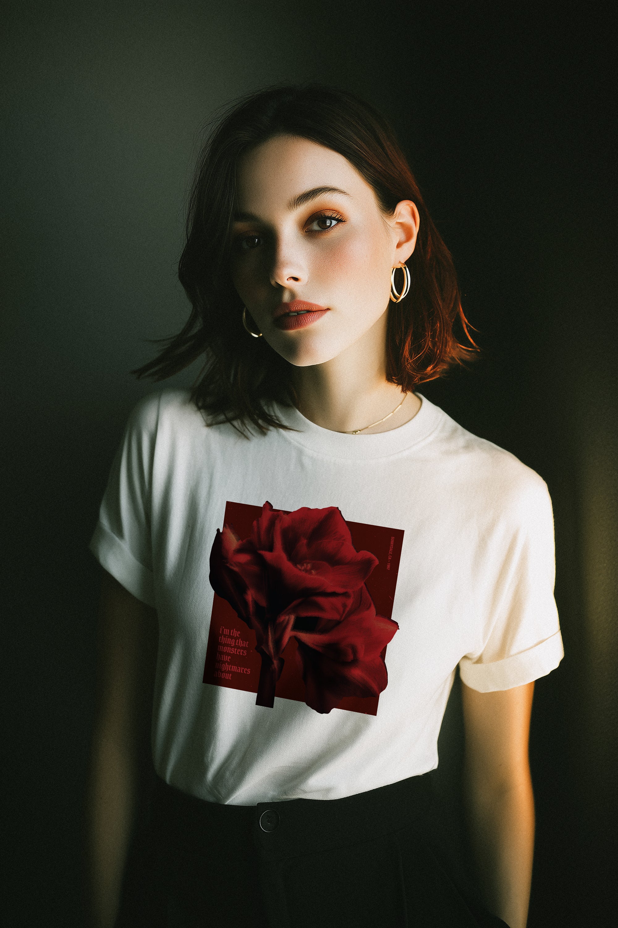 Woman wearing a white t-shirt with a red rose design against a dark background