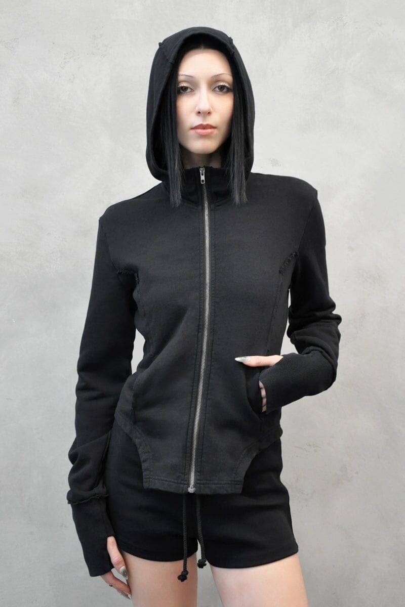 Person wearing a black hoodie and shorts on a gray background
