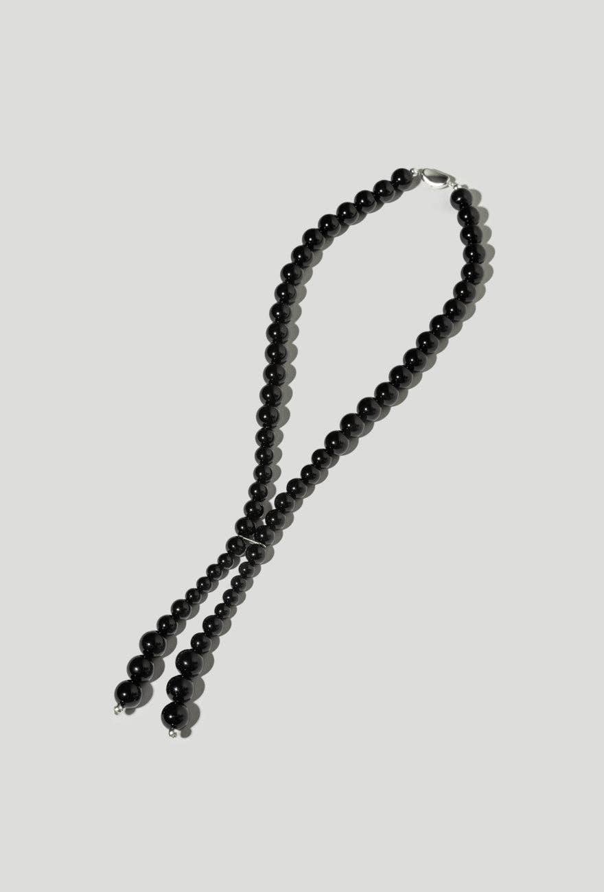 Black beaded necklace on a light gray background