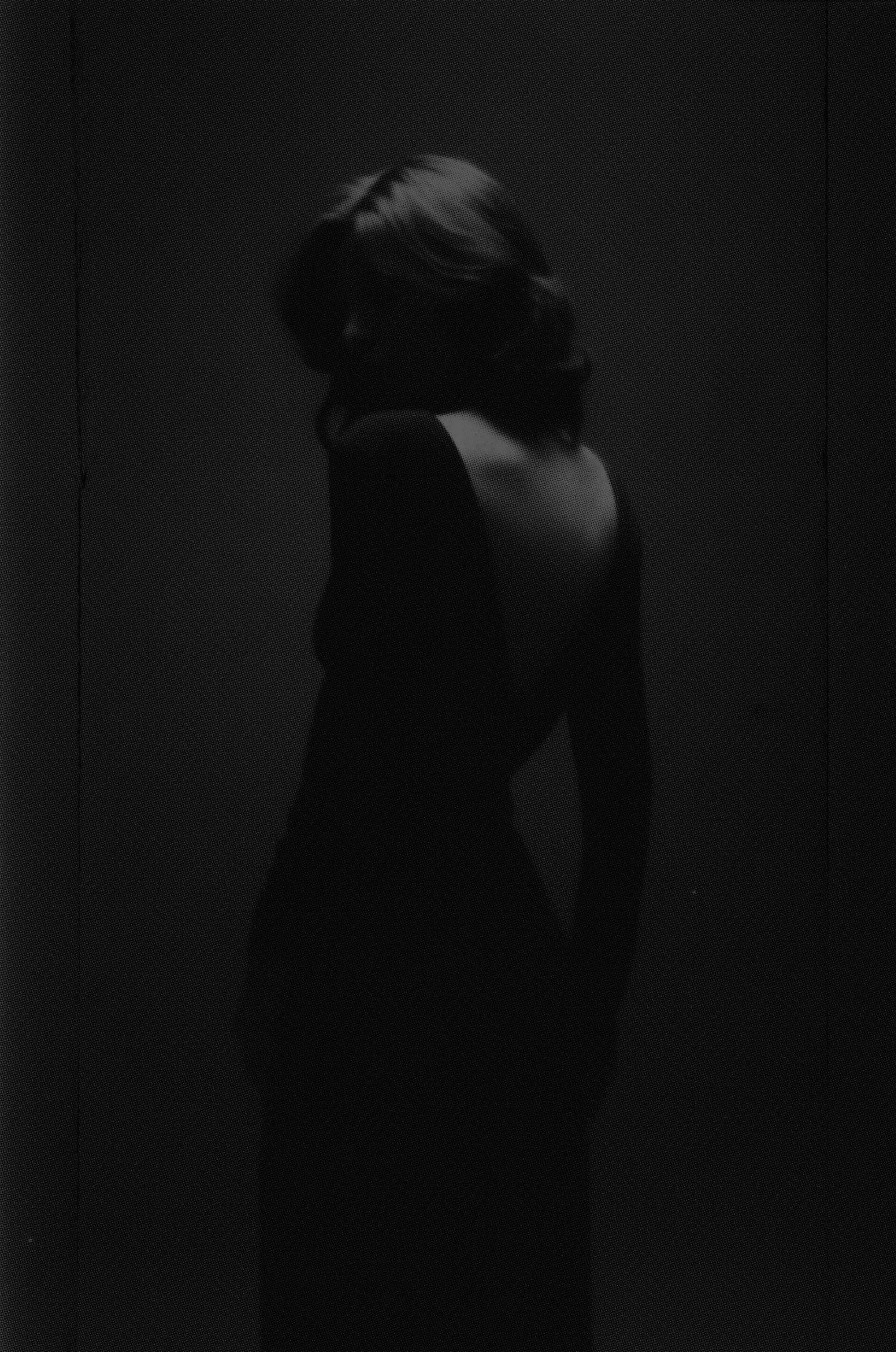 Person standing in a dark room with minimal light