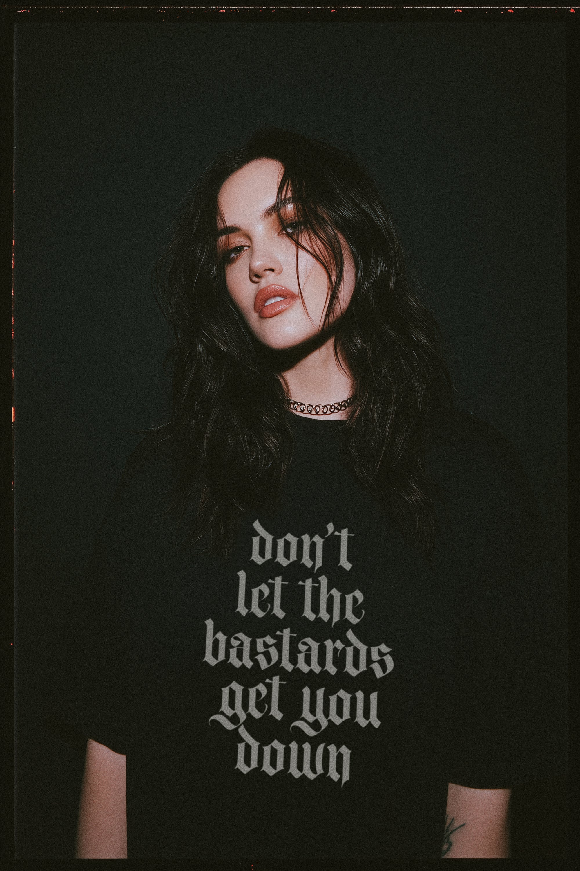 Person wearing a black t-shirt with the text Don't Let the Bastards Get You Down written in a gothic font on a dark background