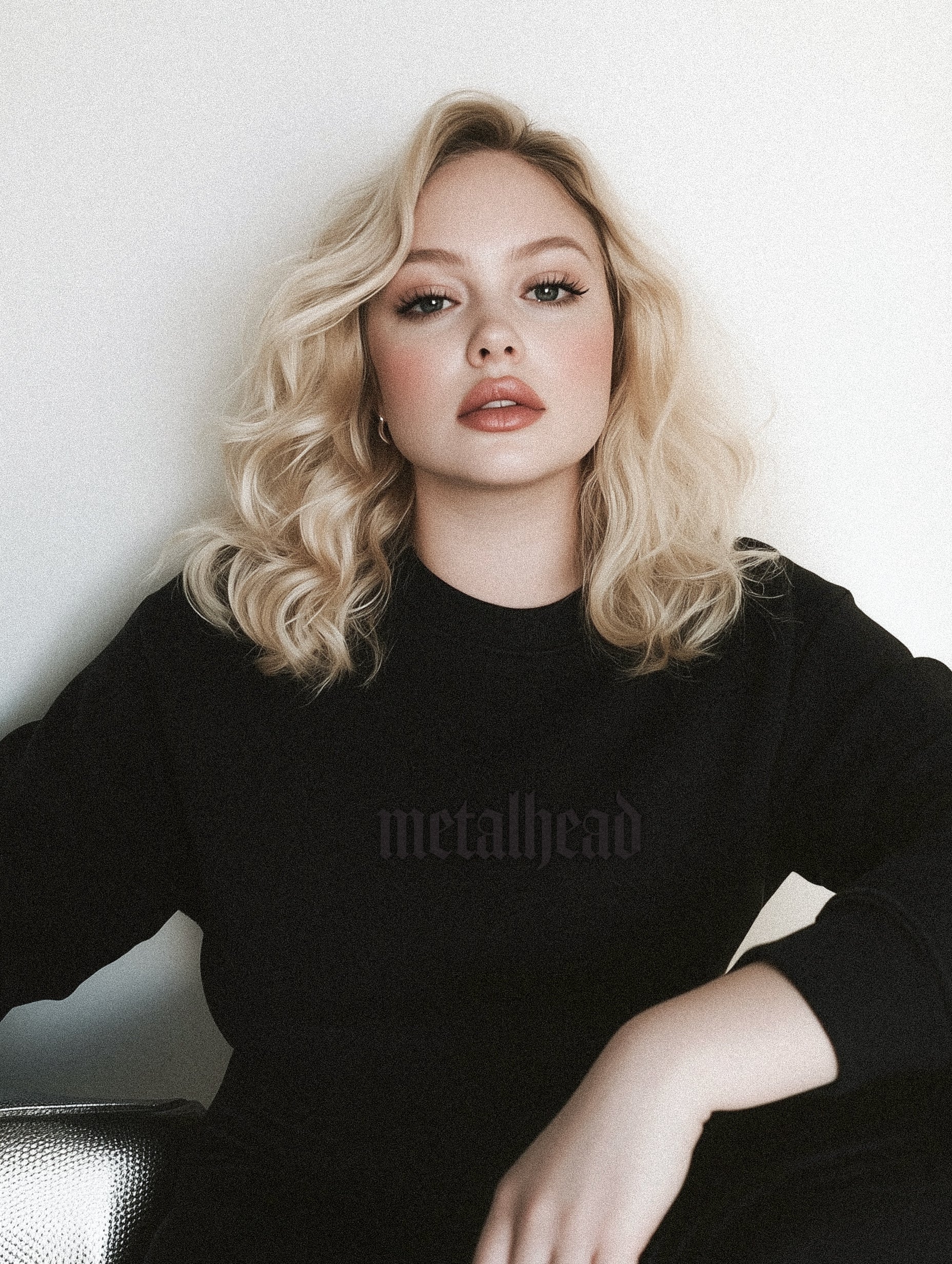 A person wearing a black crewneck sweatshirt with 'Metalhead' embroidered on the front.