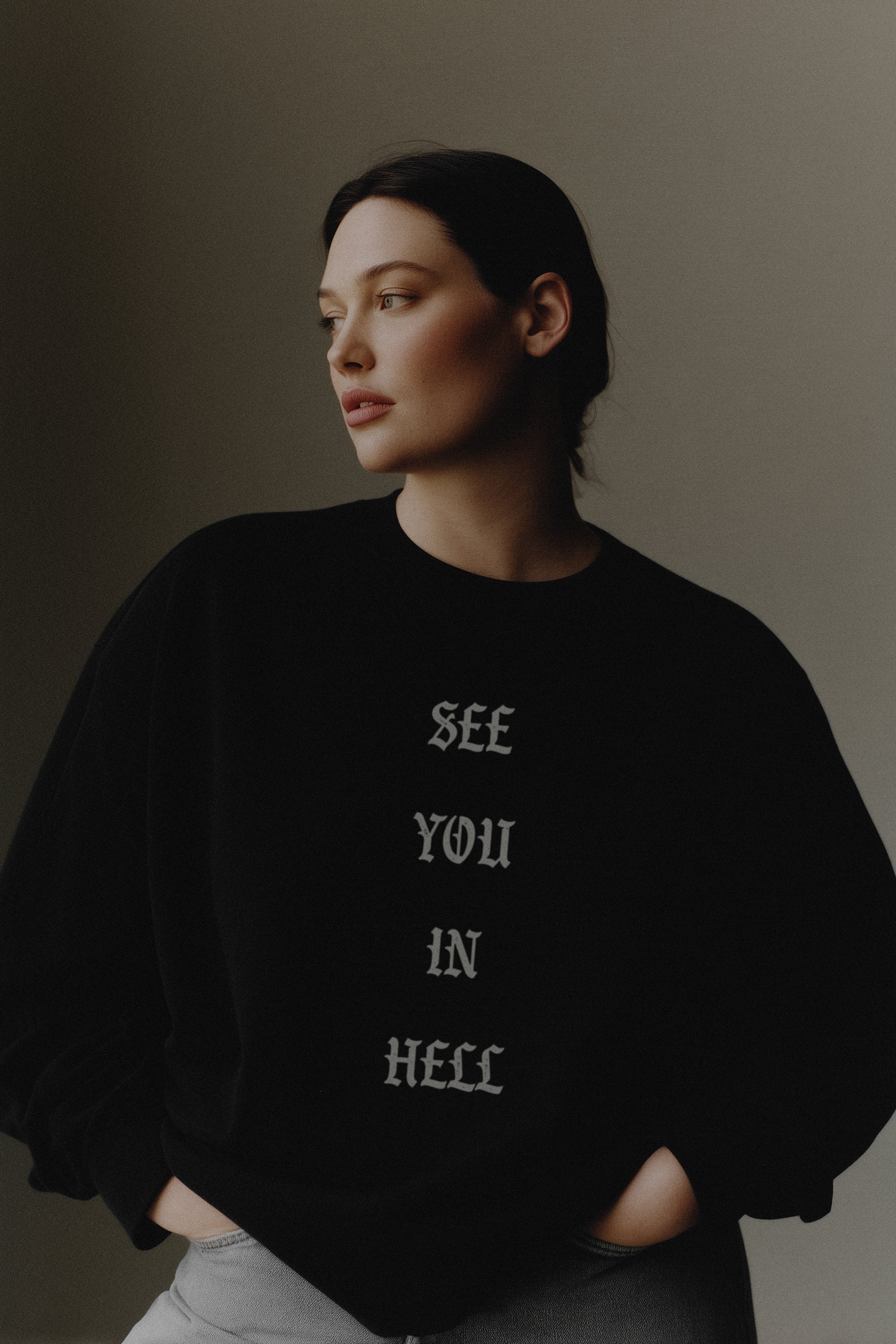 Person wearing a black sweatshirt with text 'SEE YOU IN HELL' on a plain background
