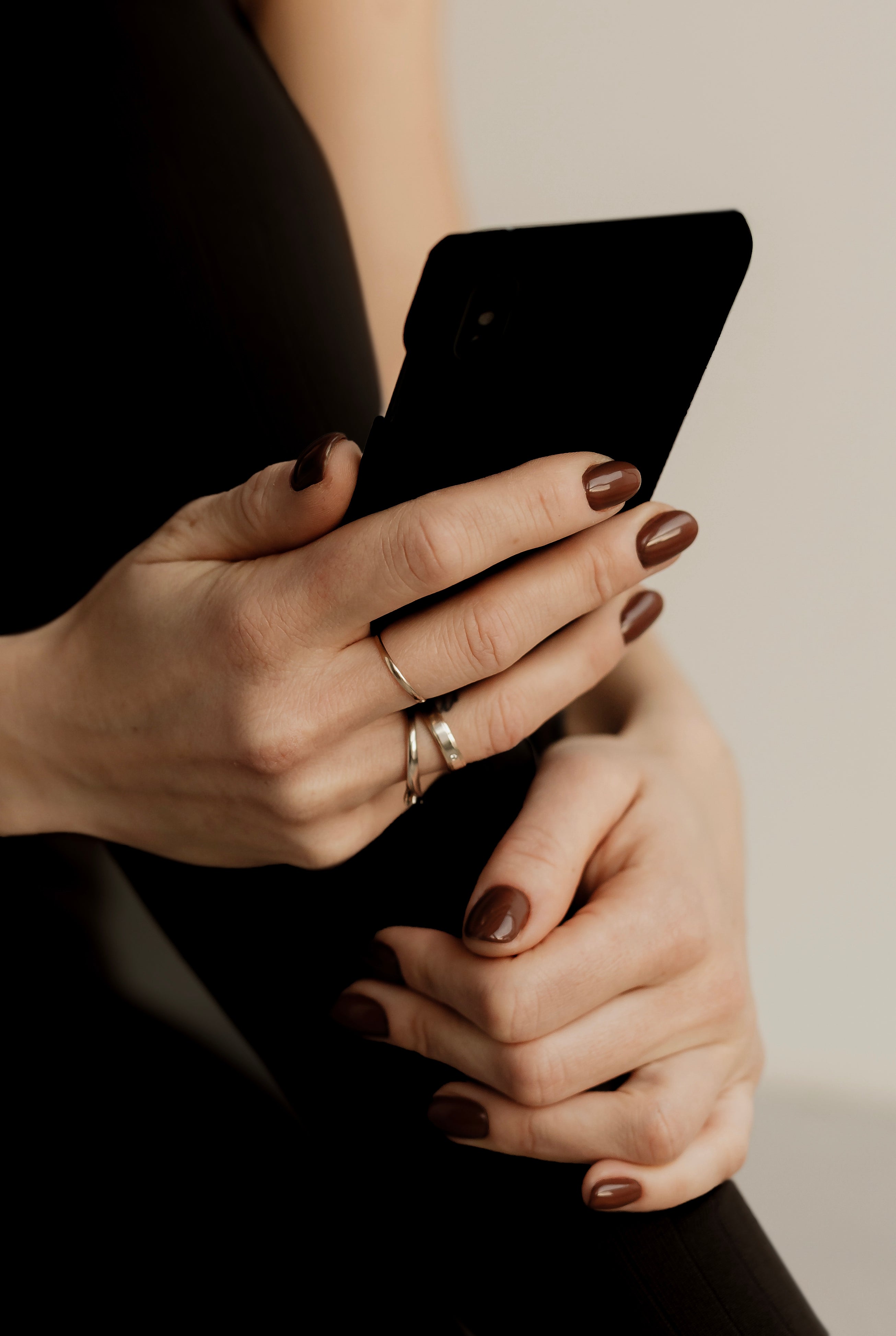 Close-up of hands holding a smartphone with a neutral background