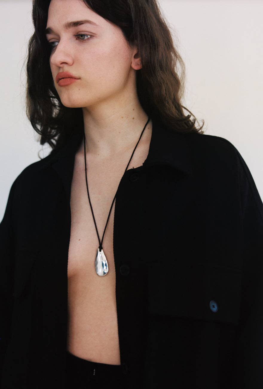 Woman wearing a black shirt with a necklace against a white background